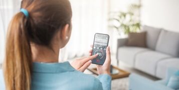 Woman,Controlling,The,Smart,Thermostat,And,Setting,Room,Temperature,Using