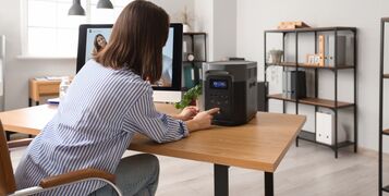 Young,Woman,Turning,Portable,Solar,Station,On,Desk,In,Office,
