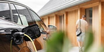 Young,Man,Plugging,A,Charger,In,Electric,Car,At,Modern