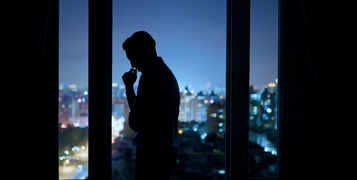 Worried,Asian,Young,Businessman,Is,Standing,Near,Windows,While,Working