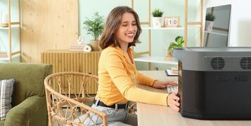 Young,Woman,Using,Portable,Power,Station,At,Workplace,In,Office